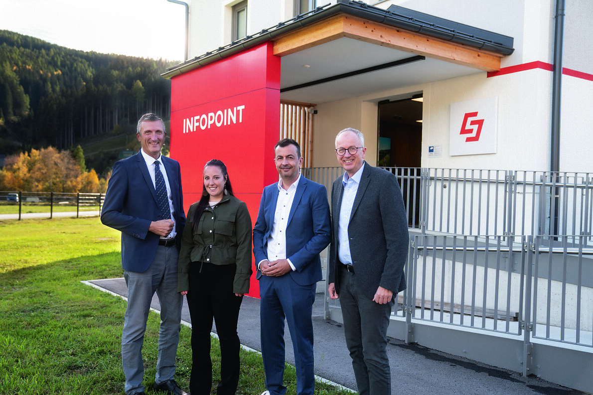 Vier Personen stehen vor einem Infopoint-Gebäude in Österreich.